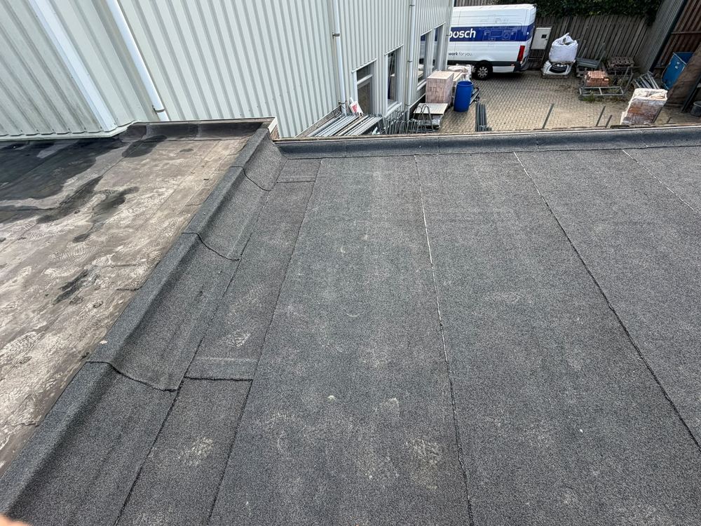 Plat dak met nieuwe bitumen dakbedekking tot tegen de gevel