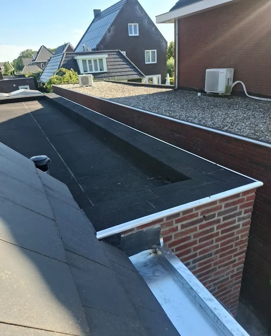 Nieuwe zinken bakgoot langs de rand van een plat bitumen dak