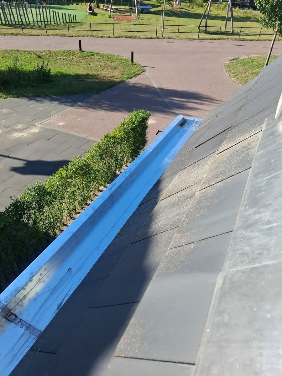 Nieuwe zinken goot met beschermfolie langs een hellend dak