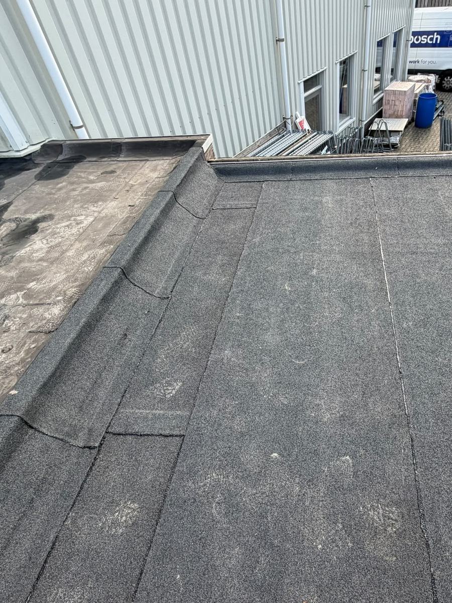 Plat dak in Nistelrode met nieuwe bitumen dakbedekking, opgezet tegen de gevel