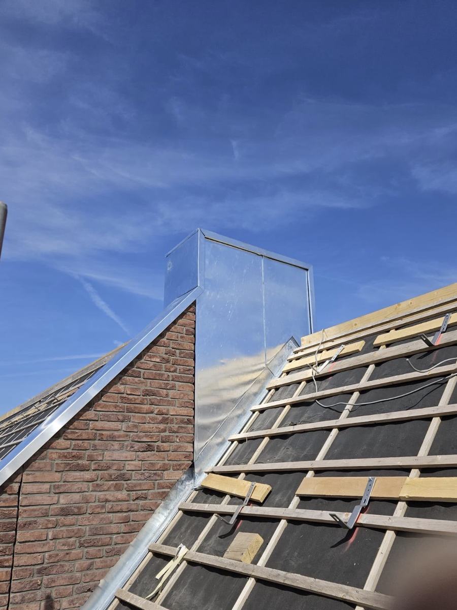 Met zink beklede schoorsteen en zinken afdekking op de topgevel van een woning in renovatie