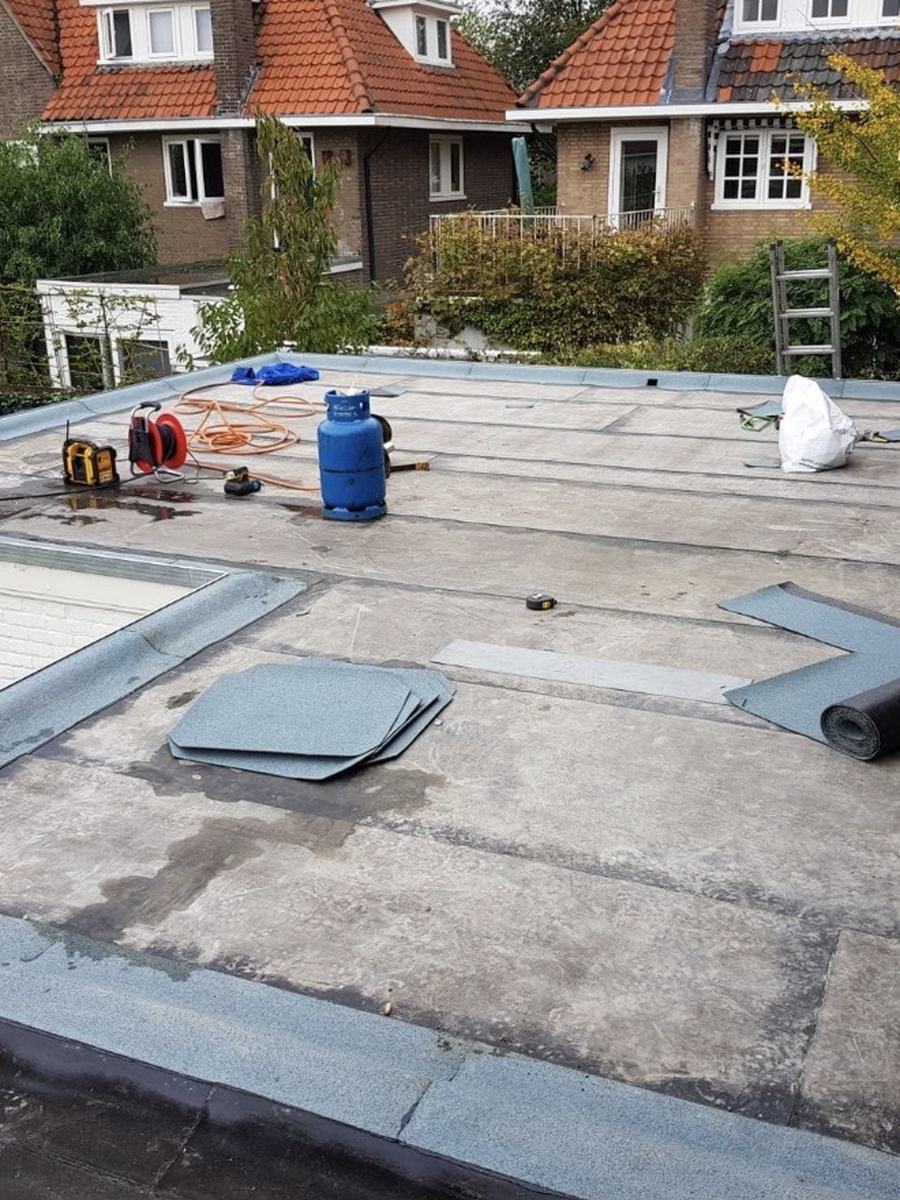 Plat dak van een woning tijdens het vernieuwen van de bitumen dakbedekking